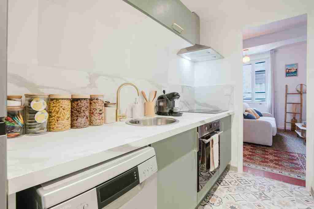Cuisine moderne et élégante avec plan de travail en marbre appareils ménagers modernes et rangements bien organisés menant à un lumineux salon accueillant